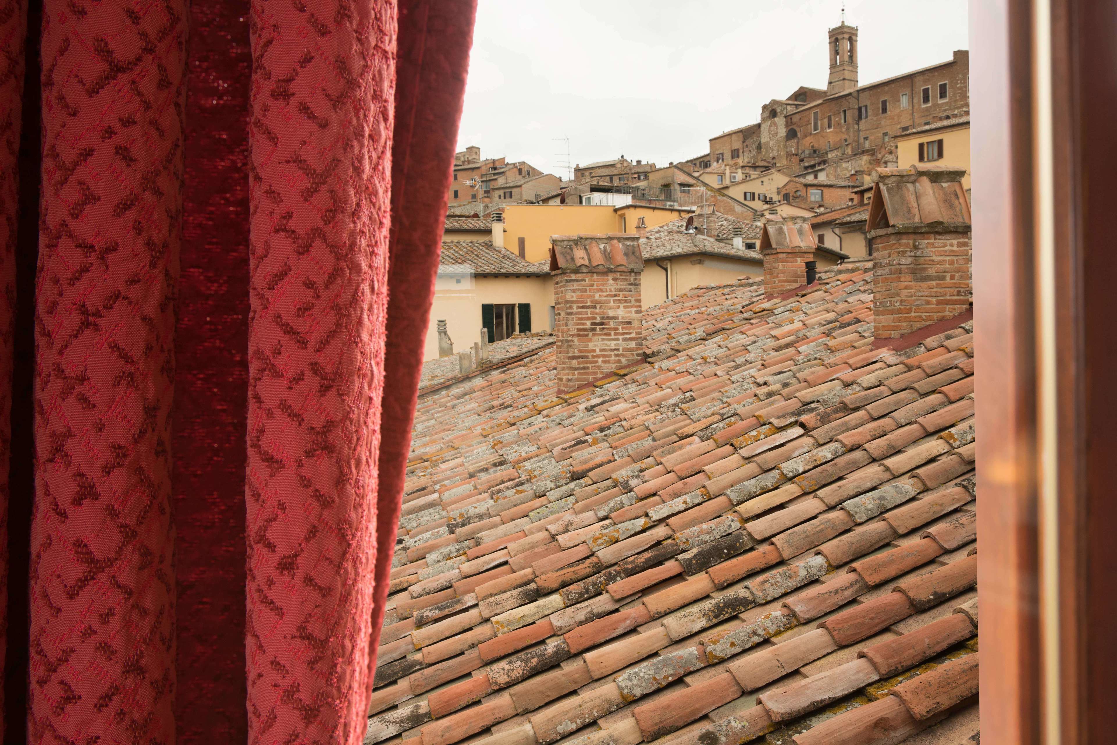 Vista de tejados de tejas terracota y un edificio histórico con una torre.