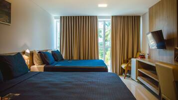 Quarto de hotel com duas camas, uma escrivaninha, televisão e janela com cortinas.