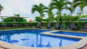 A swimming pool with lounge chairs and palm trees.