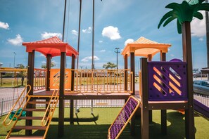 A playground with multiple play structures, including slides and climbing areas, set on artificial grass. - Hotel 10 Itajai (Itajai)