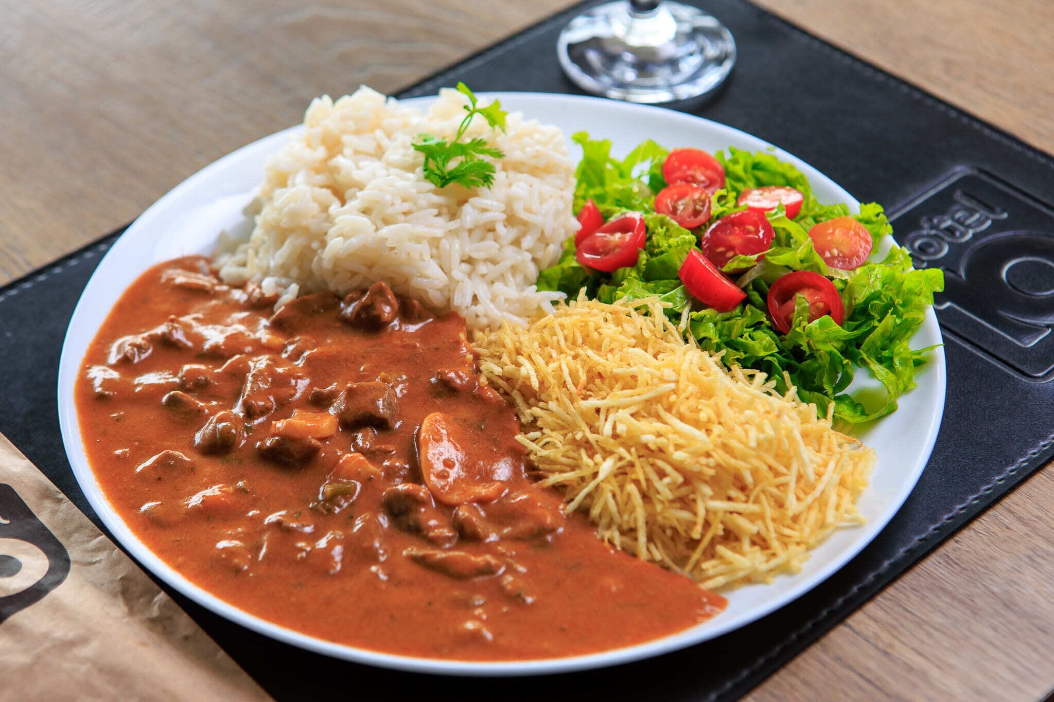 A plate with rice, a meat dish, shredded cheese, and a salad.