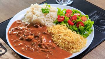 Un plato de arroz, un guiso de carne, queso rallado y una ensalada.