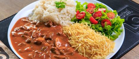 A plate with rice, a meat dish, shredded cheese, and a salad.