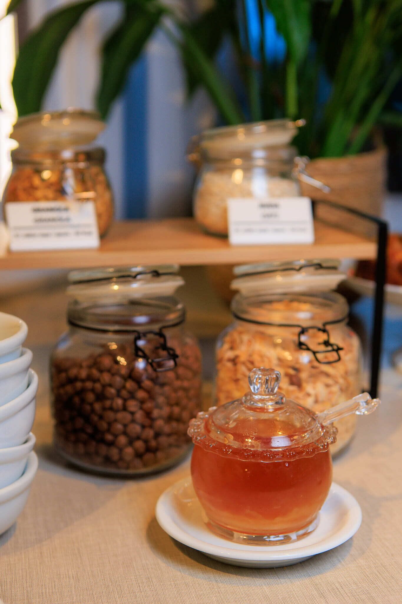 A display of jars with labels, a glass teapot, and white bowls on a table.