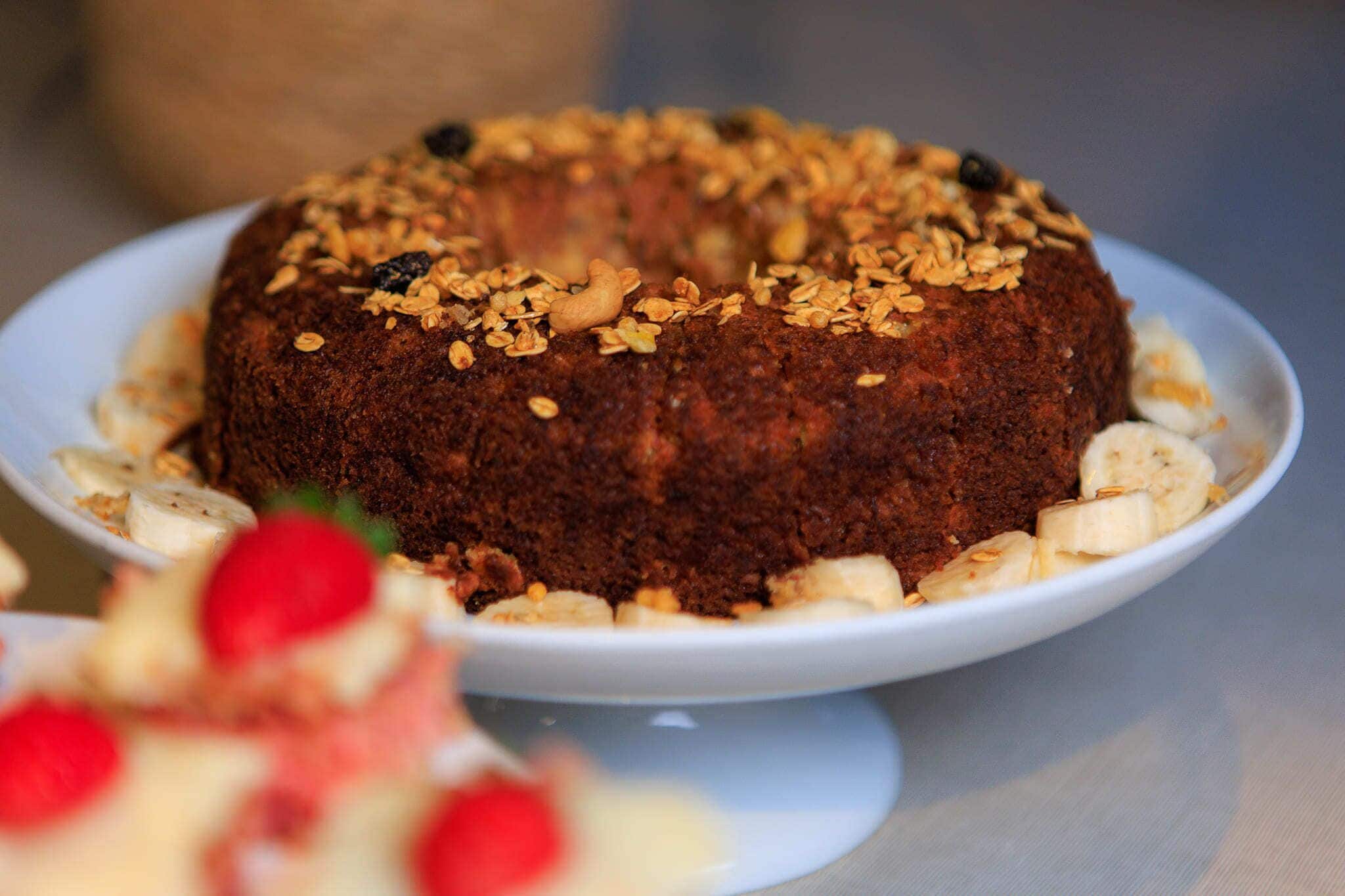 Een bundtcake met toppings op een wit bord.