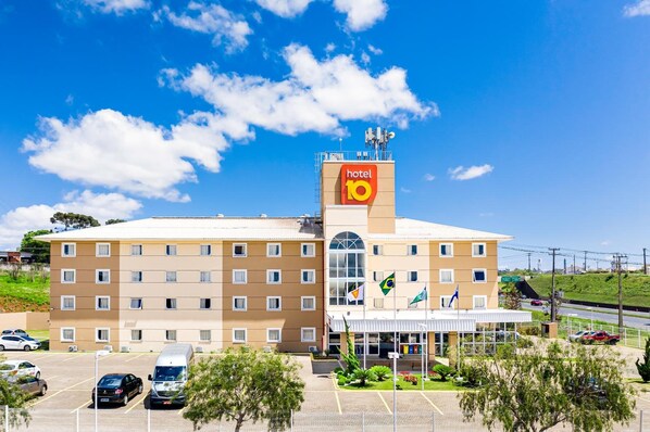 A hotel with a prominent 'hotel 10' sign, multiple floors, and a parking lot with several cars. - Hotel 10 Ponta Grossa (Ponta Grossa)