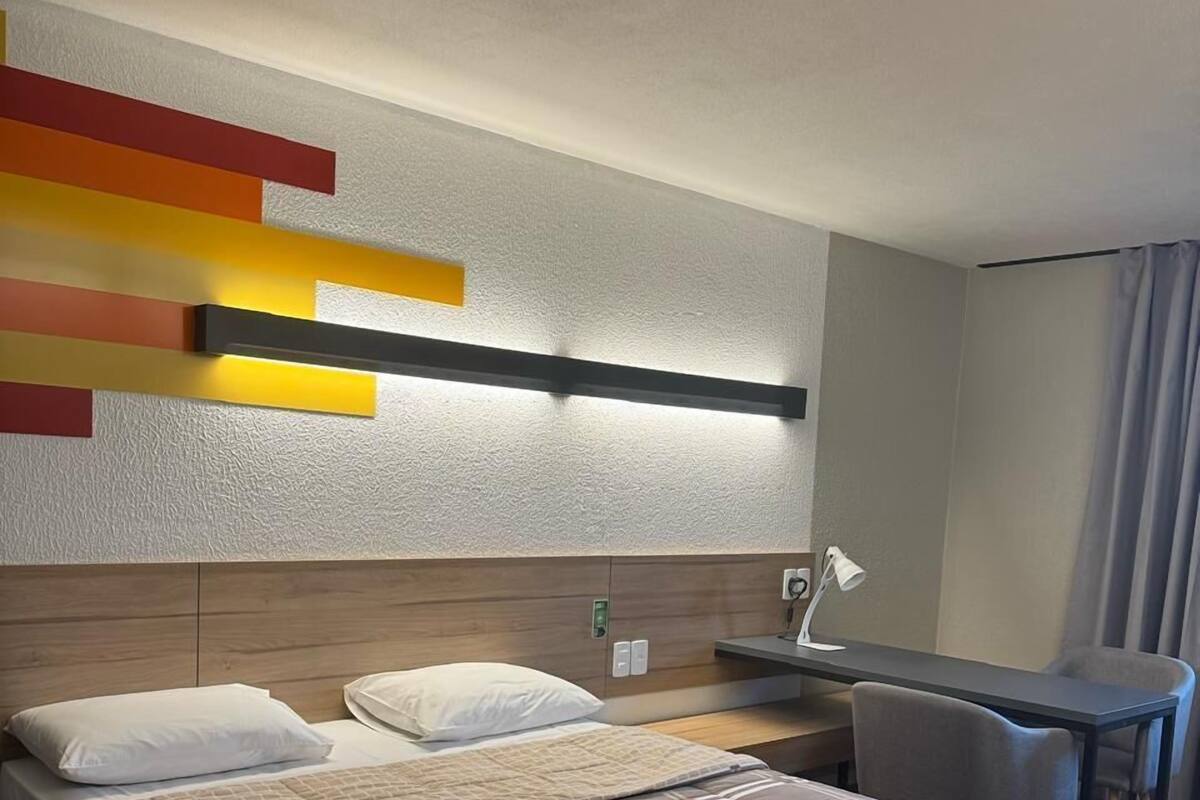 Una habitación de hotel con cama, mesita de noche y escritorio con silla.