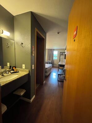 Una habitación de hotel con baño, cama y escritorio.