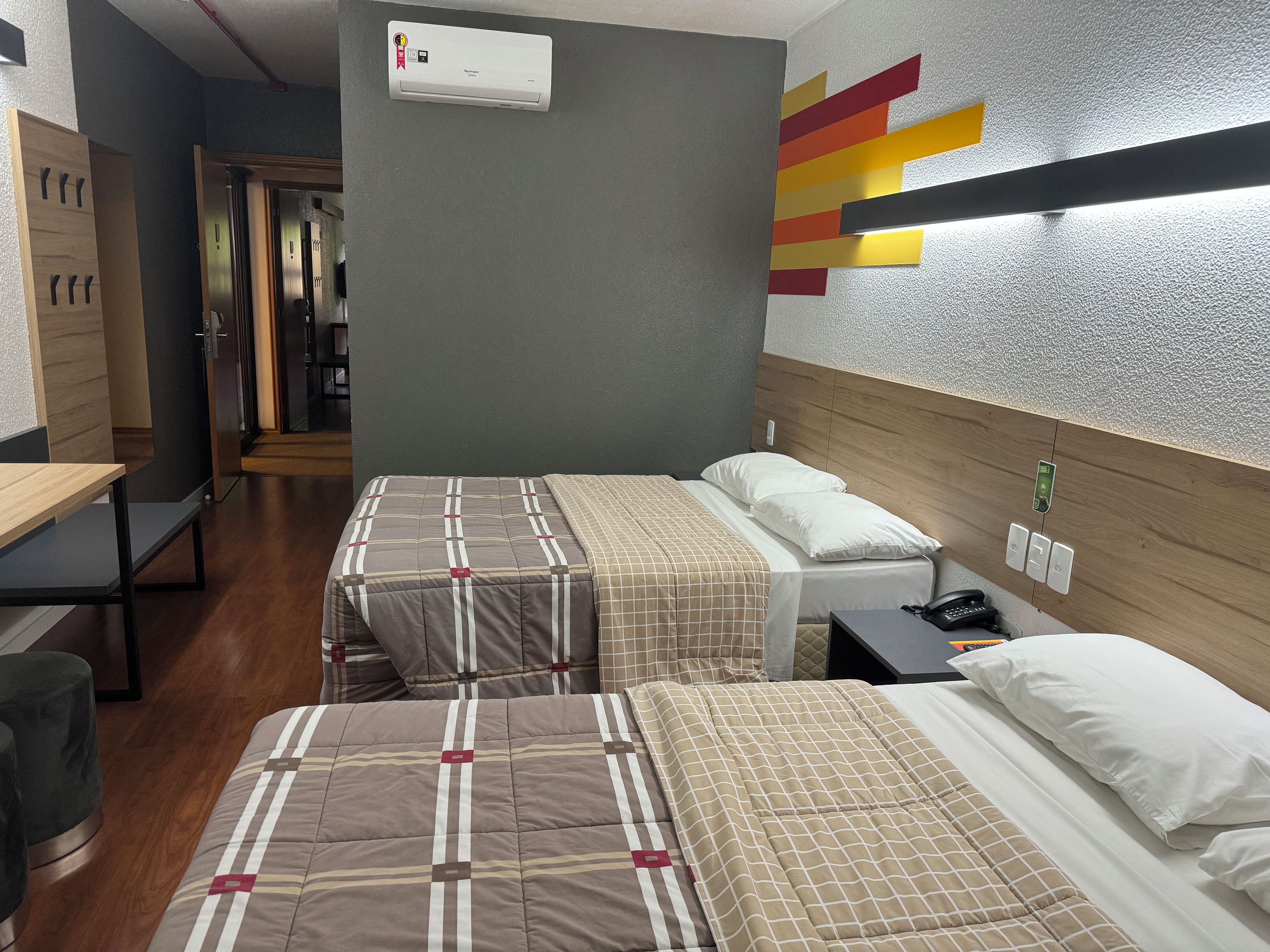 A hotel room with two beds, a desk, and a wardrobe.