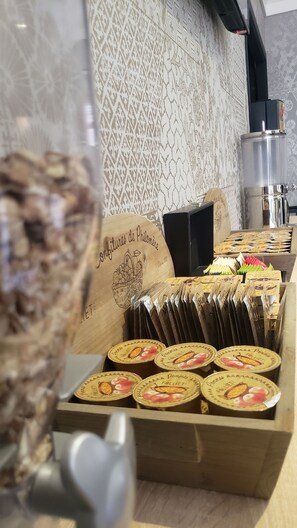 Une présentation de produits alimentaires emballés dans une boîte en bois, avec un mur à motifs et une machine à café en arrière-plan.