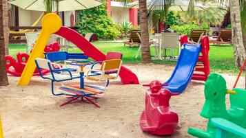Un parque infantil con columpios, toboganes y un balancín.