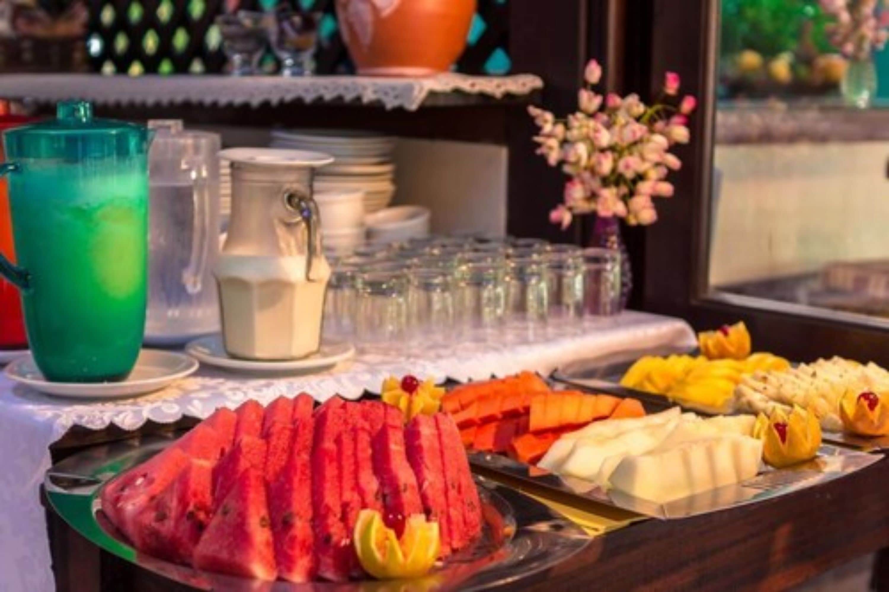 Una mesa de buffet con diversas frutas y una jarra de leche.