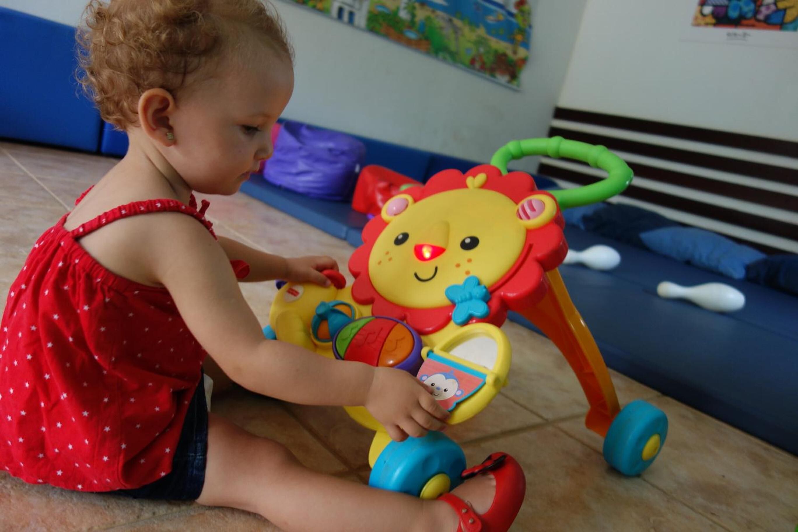 Un enfant joue avec un lion en plastique qu’il peut pousser devant lui.