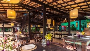 A restaurant with wooden tables and chairs, hanging lamps, and a bar area. - Porto Zarpa Hotel (Mata de São João)
