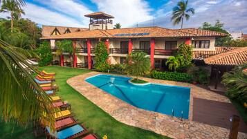 A resort with a swimming pool, lounge chairs, and a well-maintained garden.