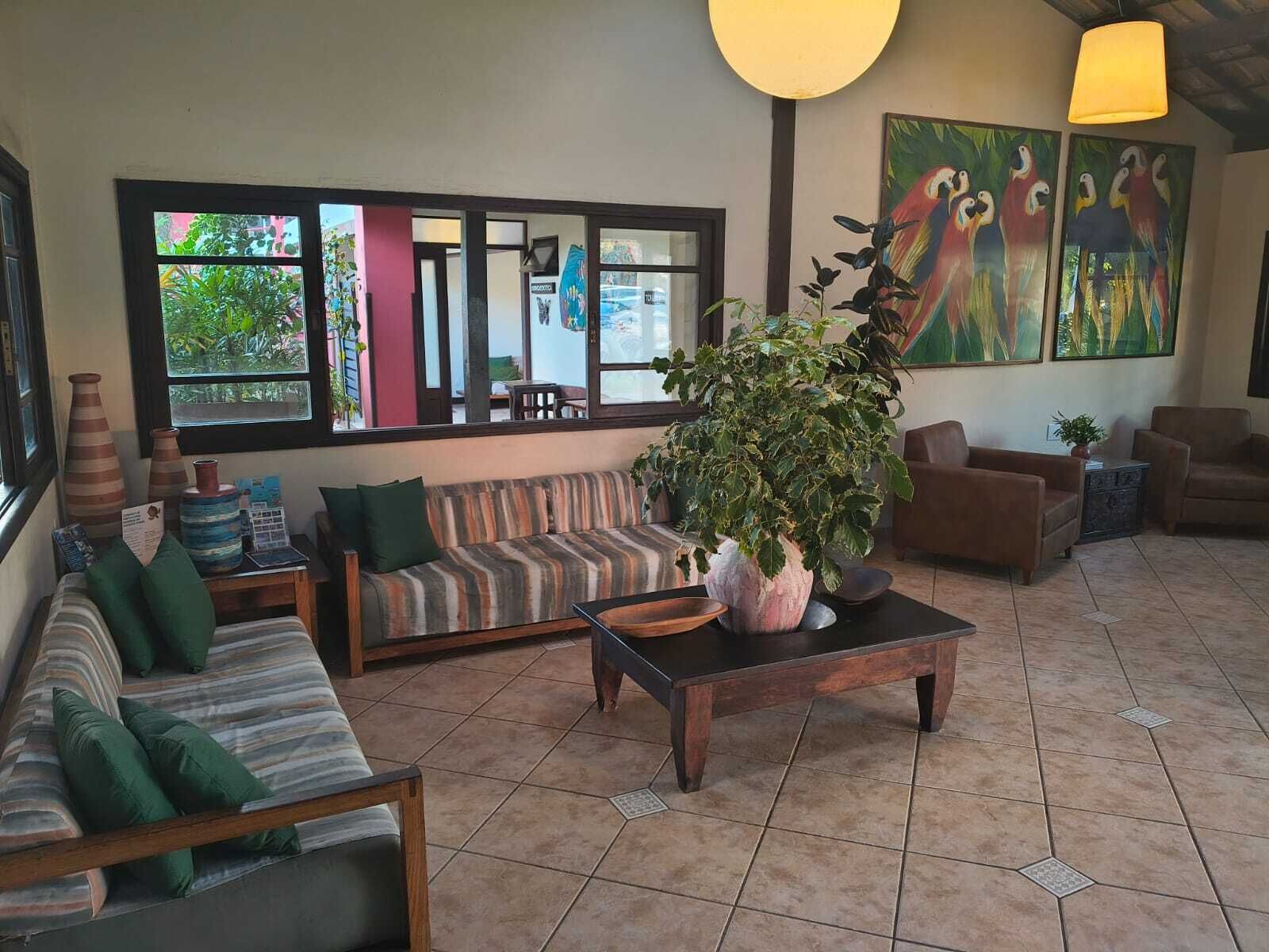 A furnished living area with a sofa, armchairs, a coffee table, and a large window with a view of greenery.