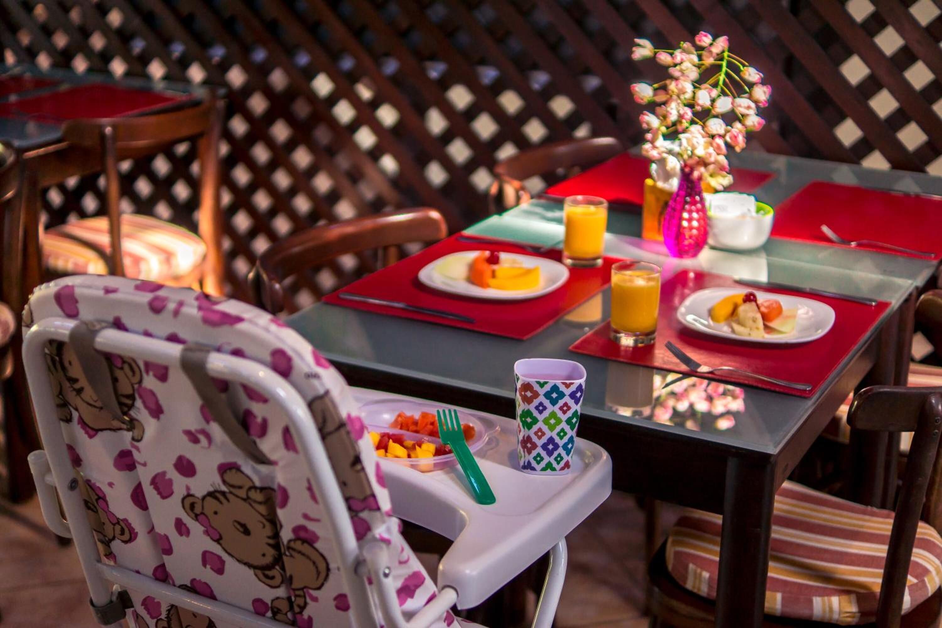 Un espace repas avec une table haute, des chaises et une chaise haute pour bébé ornée d’un motif Hello Kitty.