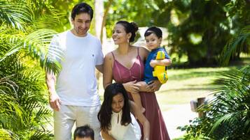 A family walking in a lush garden with palm trees and a paved path.