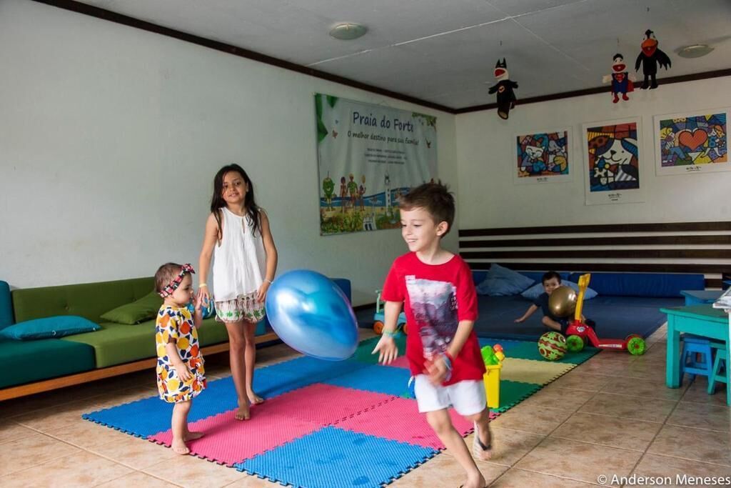 Una habitación con un sofá verde, esteras de colores y juguetes infantiles.