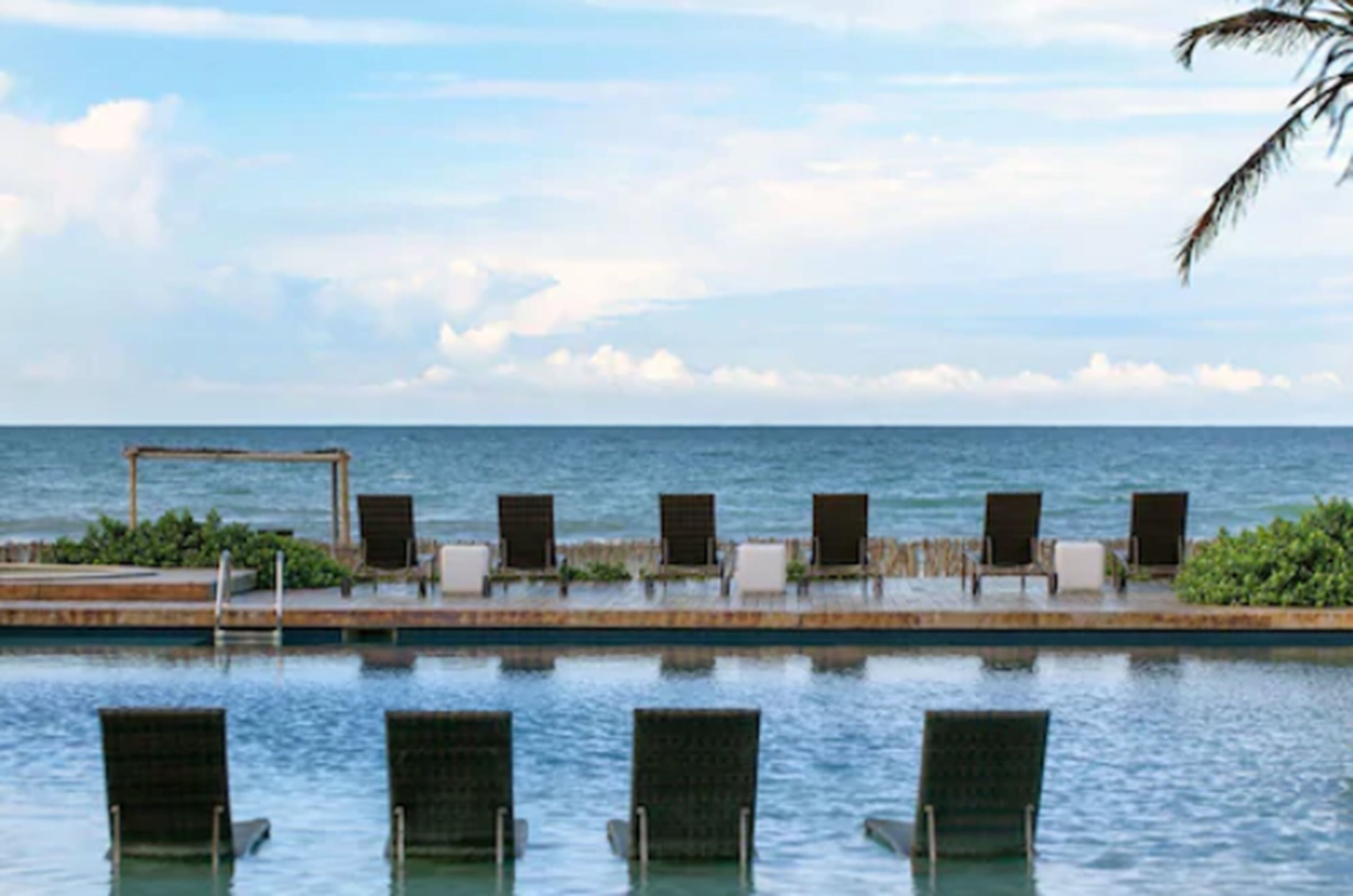 Zona de piscina con sillones de descanso y vista al mar.