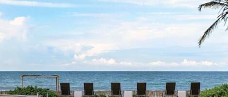 Zona de piscina con sillones de descanso y vista al mar.