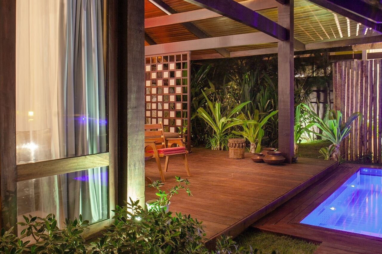 Un terrazzo in legno con piscina, circondato da piante e un recinto in legno.