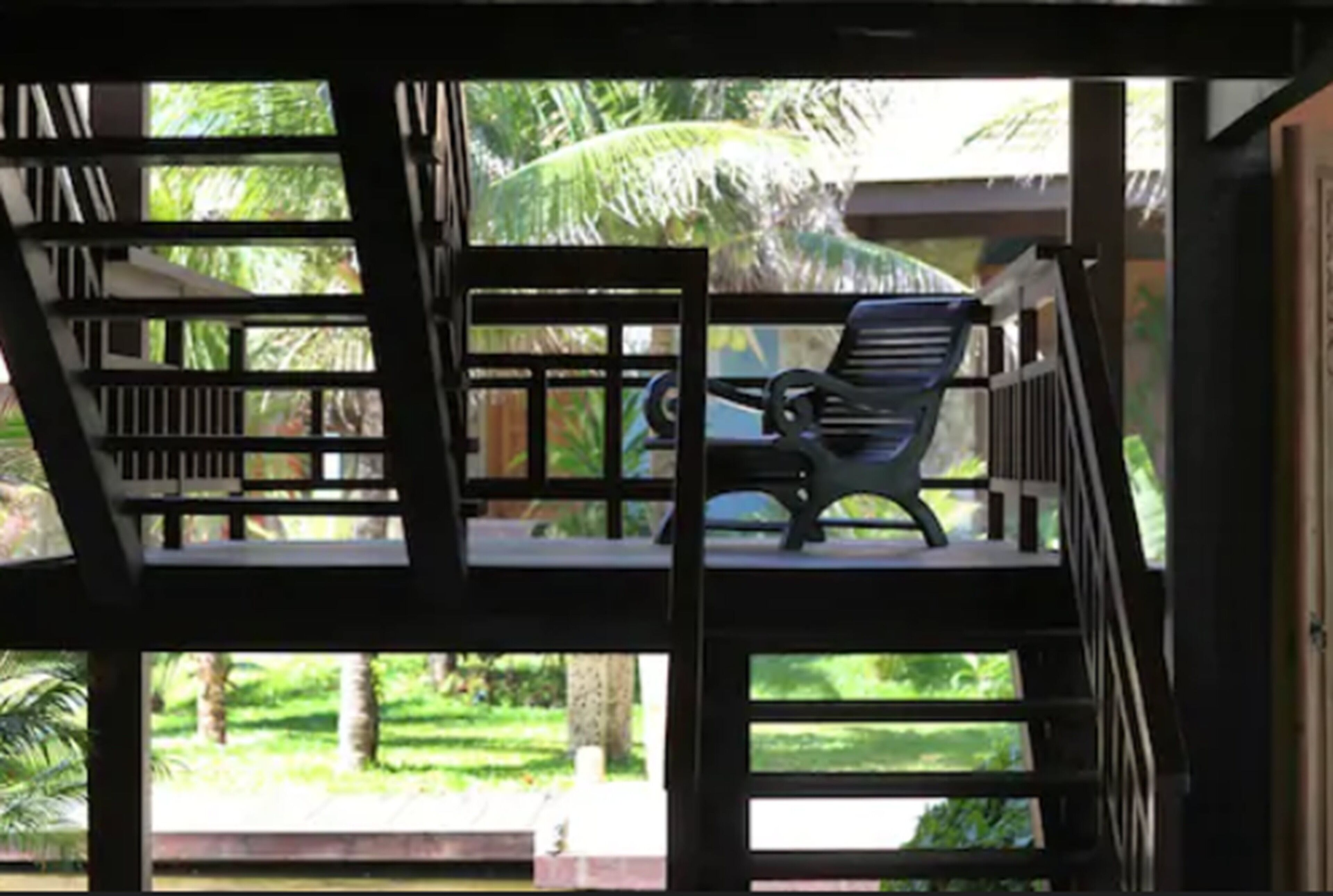 A multi-level outdoor seating area with a chair on the upper level and a view of a lush garden.