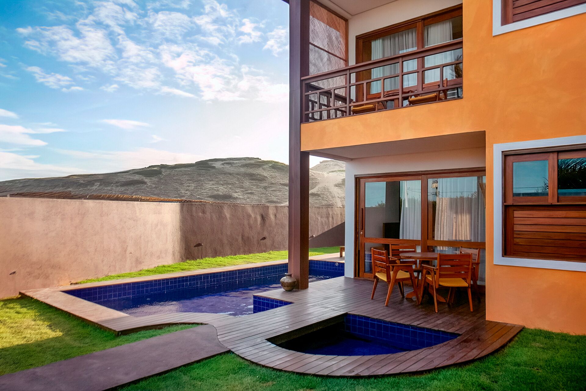 Un edificio de dos pisos con balcón, piscina y patio.
