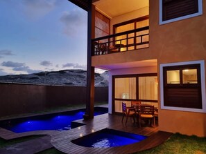 A two-story building with a balcony, a pool, and a dining area.