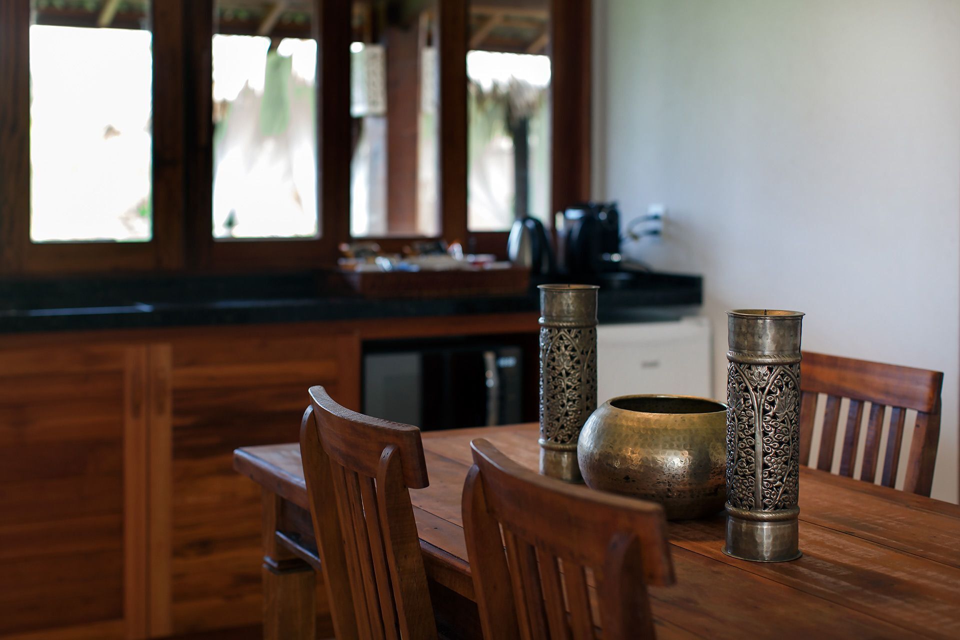 A wooden dining table with two ornate metal vases and a bowl.
