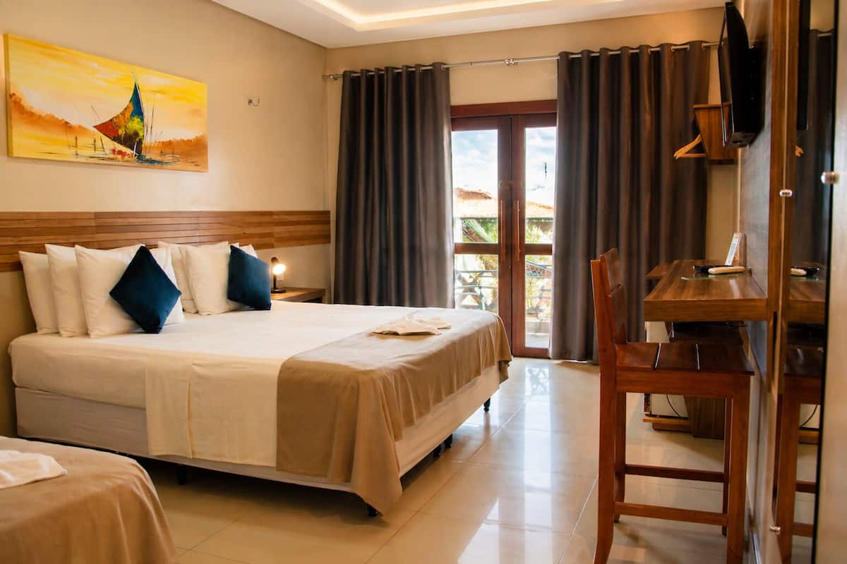 Une chambre d’hôtel avec un lit, un bureau, une télévision et un balcon avec des rideaux.