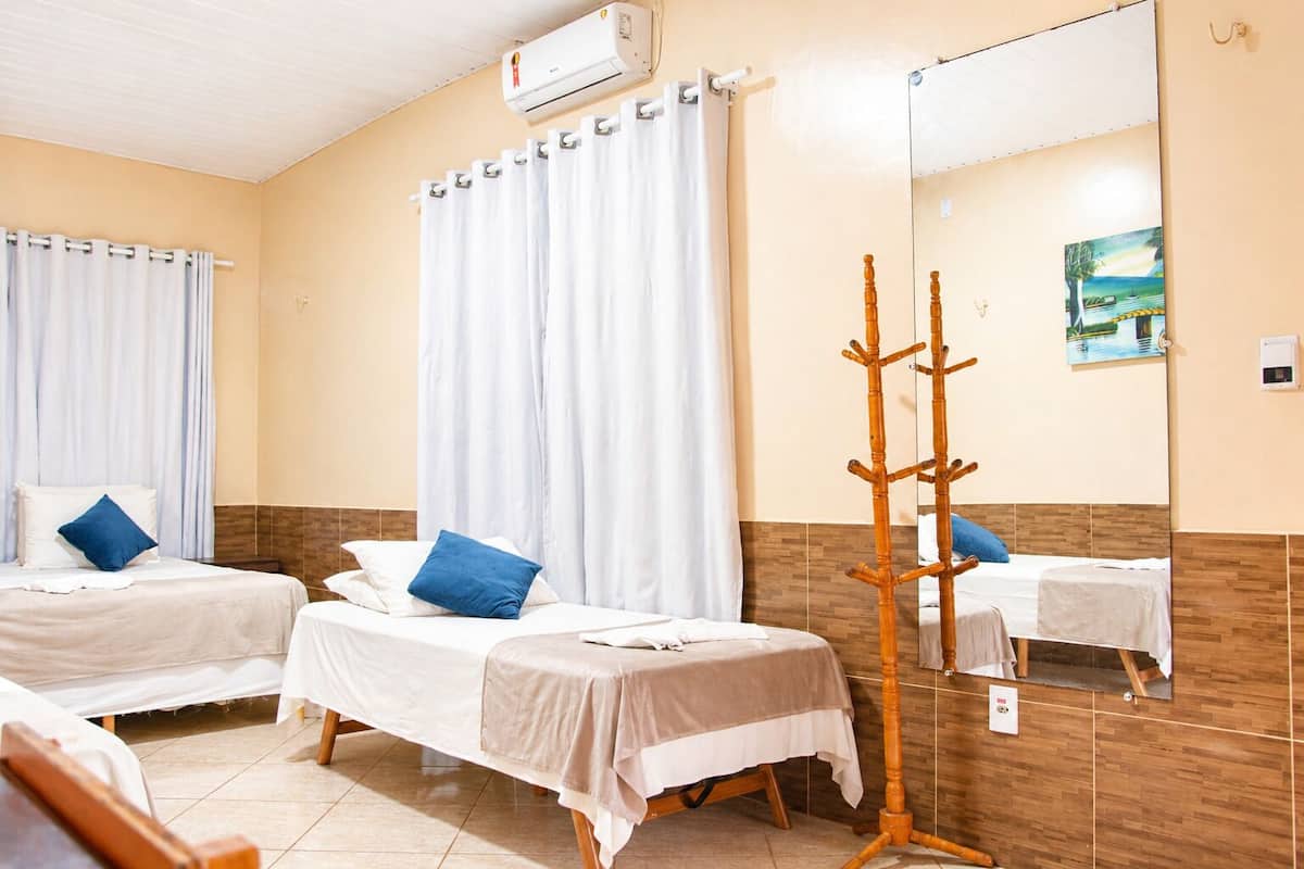Une chambre d’hôtel avec deux lits, un miroir et un porte-manteau en bois.