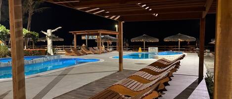 A pool area with lounge chairs and umbrellas, a covered seating area, and a sign that reads "JAGUAR".