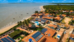 Vista aérea de un hotel costero con paneles solares, piscina y playa.