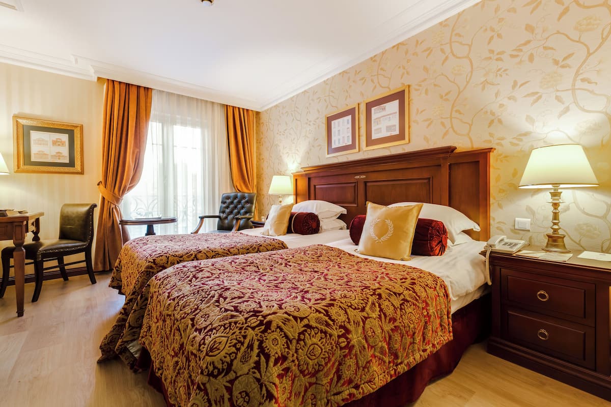 Una habitación de hotel con dos camas, un escritorio, una silla y una lámpara.