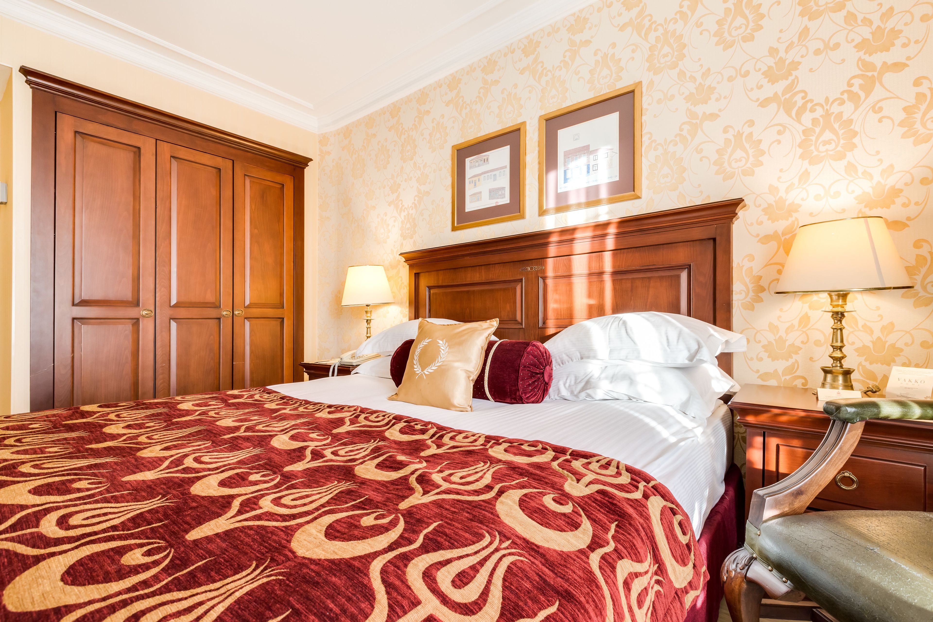 Habitación de hotel con una cama grande, un armario de madera, dos lámparas de noche y un cuadro enmarcado en la pared.