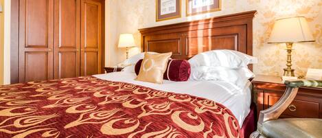 Habitación de hotel con una cama grande, un armario de madera, dos lámparas de noche y un cuadro enmarcado en la pared.
