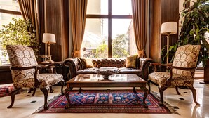 A luxurious living room with a large window, elegant furniture, and a decorative rug. - Gordion Hotel - Special Class (Ankara)
