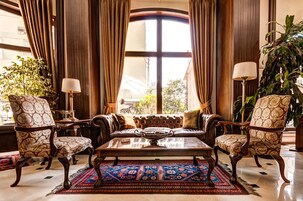 Un salón lujoso con un ventanal grande, muebles elegantes y una alfombra decorativa.