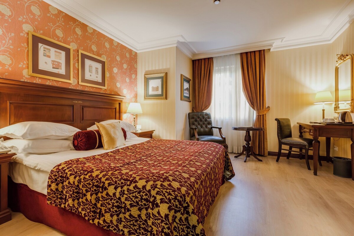Habitación de hotel con una cama grande, un escritorio, una silla y una mesita.