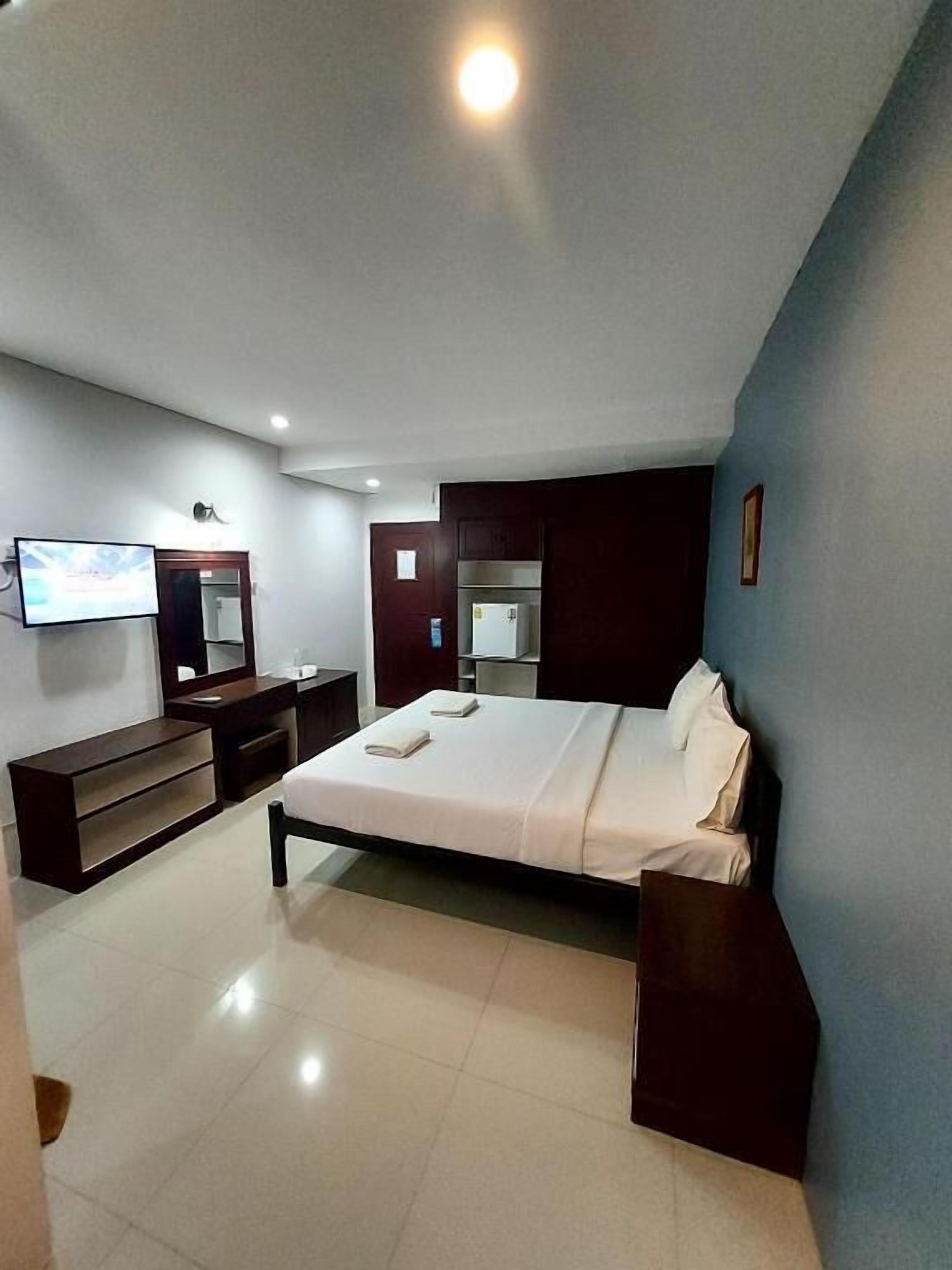 A modern bedroom with a bed, a TV, a mirror, and a wardrobe.