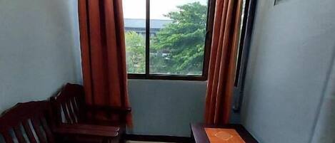 A room with a window, a wooden bench, and a small table with a mat.