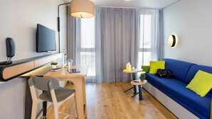 Een moderne woonkamer met een bank, een bureau met stoel, een televisie en een lamp.