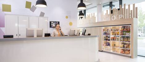 A modern reception area with a counter, a digital screen, and a display case with snacks.