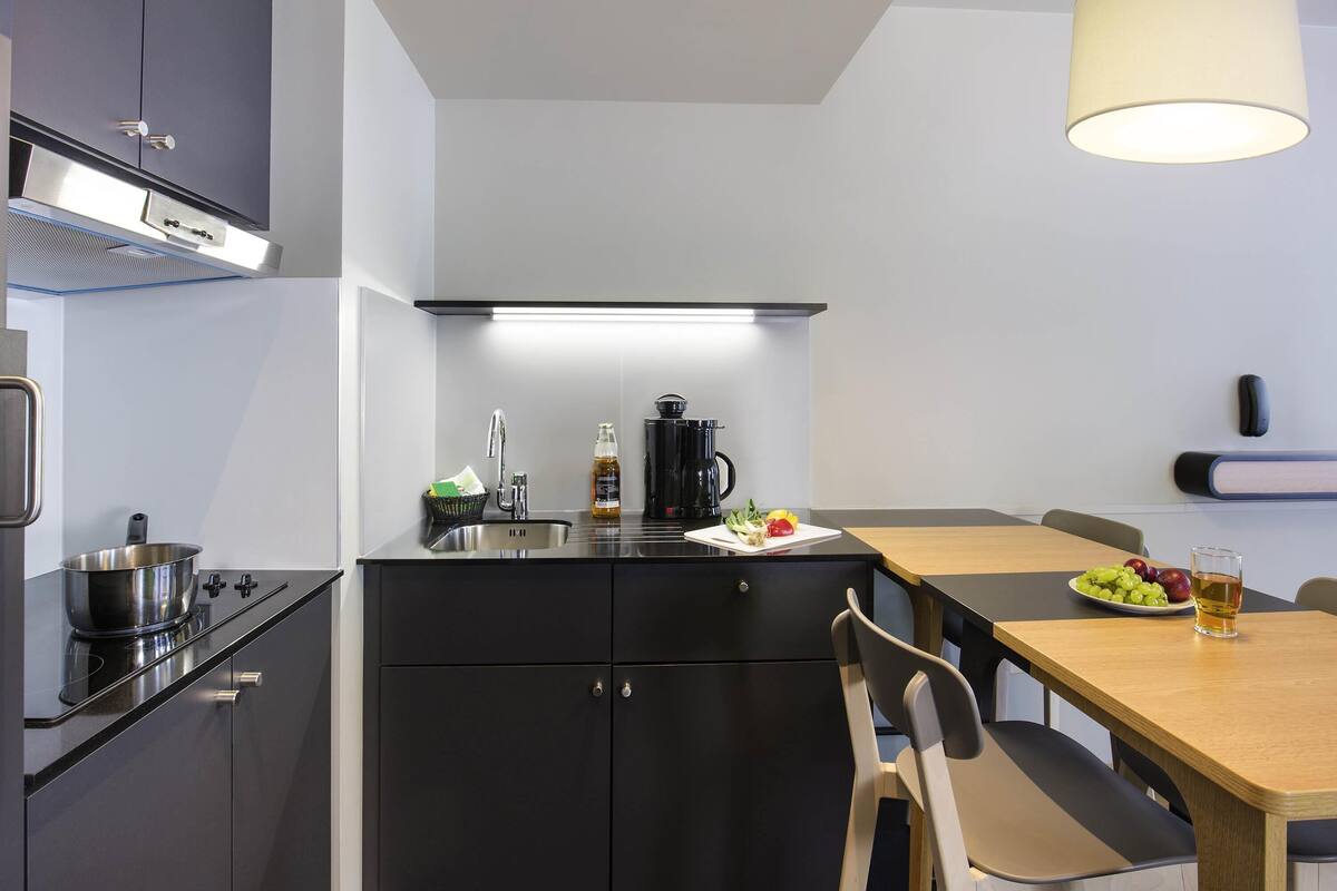 Een moderne keuken met een fornuis, spoelbak en een eethoek met tafel en stoelen.