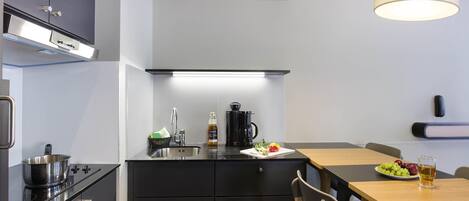 Una cocina moderna con estufa, pileta y comedor con mesa y sillas.