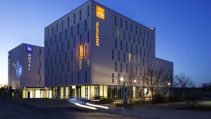 Een modern hotel met een opvallend 'APARTHOTEL' bord, een 'HOTEL' bord, en een 'HOTEL' bord met 'ibis' branding.