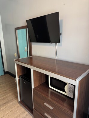 A compact kitchenette with a built-in microwave, a small refrigerator, and a flat-screen TV mounted on the wall. - Europa Hotel (San Francisco)