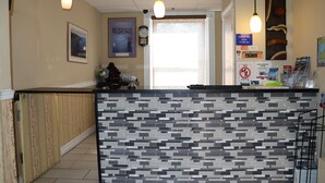 A reception area with a tiled counter, a clock, and a framed picture on the wall. - Europa Hotel (San Francisco)