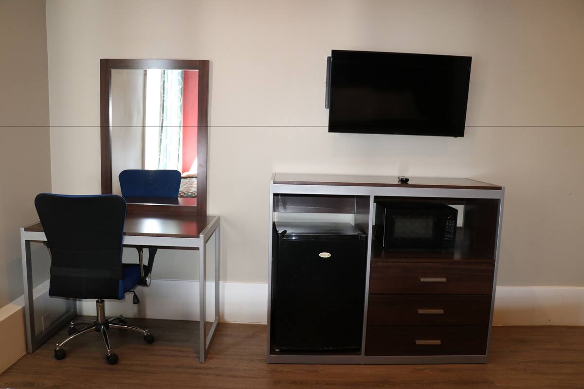 Ein Zimmer mit Schreibtisch, Stuhl und einer Kommode mit Schubladen.